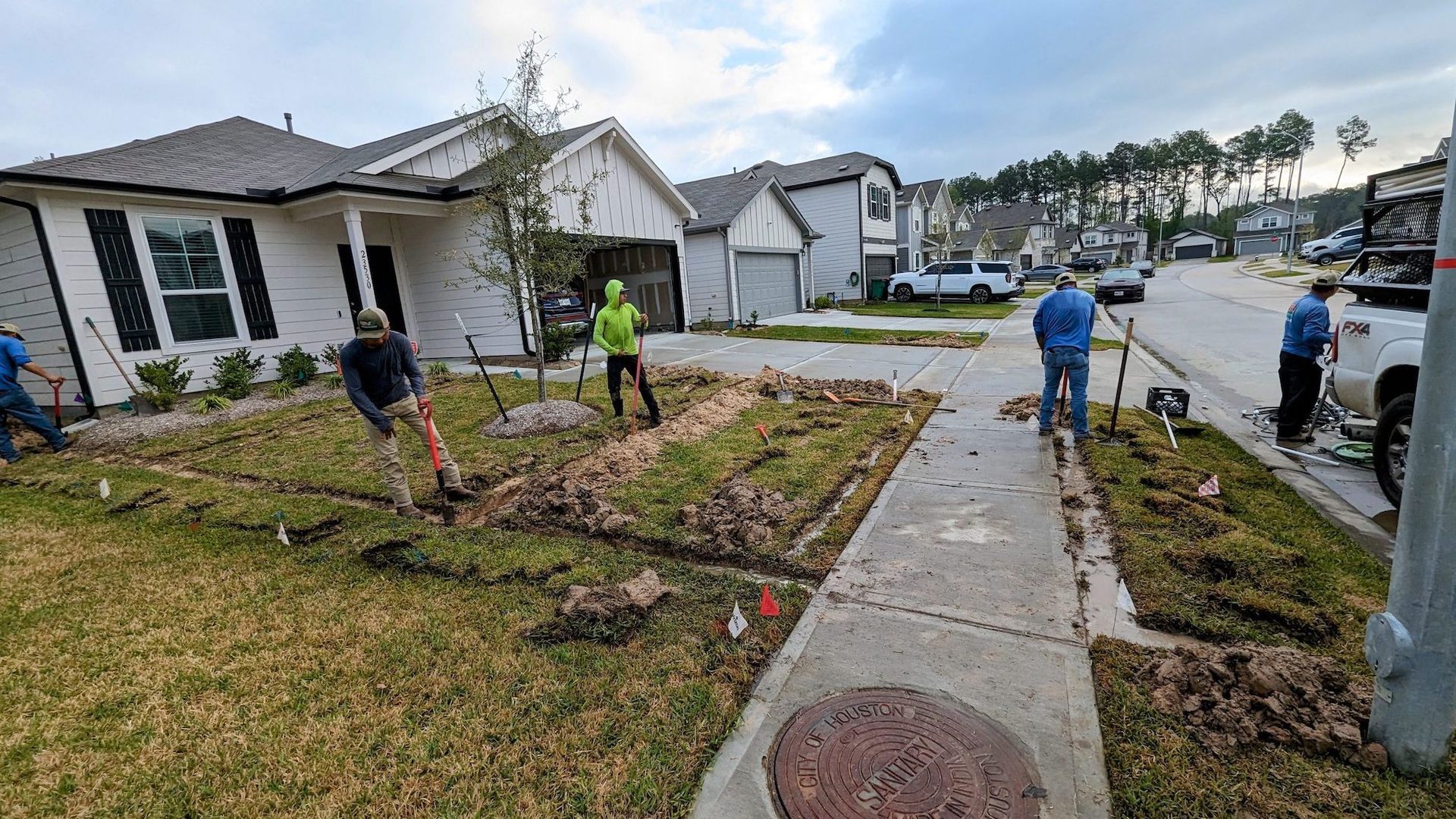 A group of people are working on a lawn in front of a house.