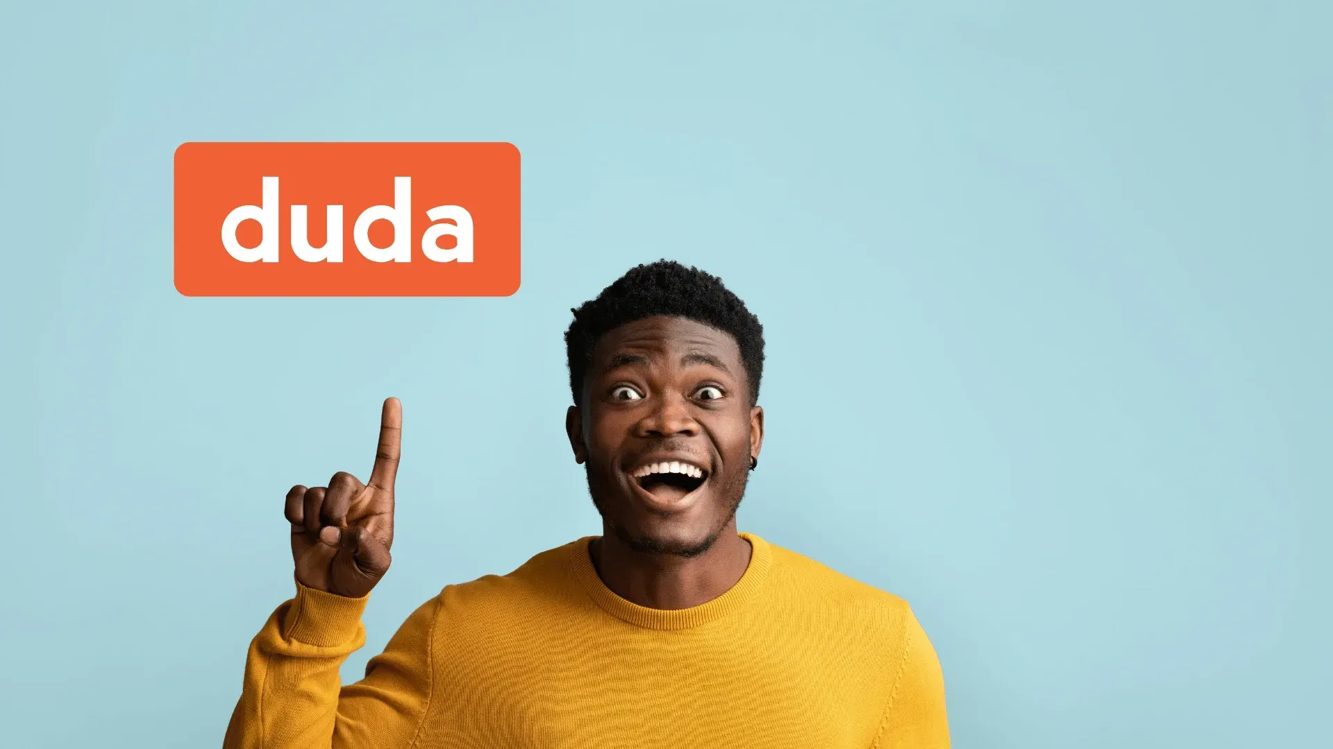 A man in a yellow sweater is pointing up with his finger.