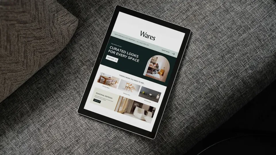 Tablet displaying the Waves website on a gray sofa.