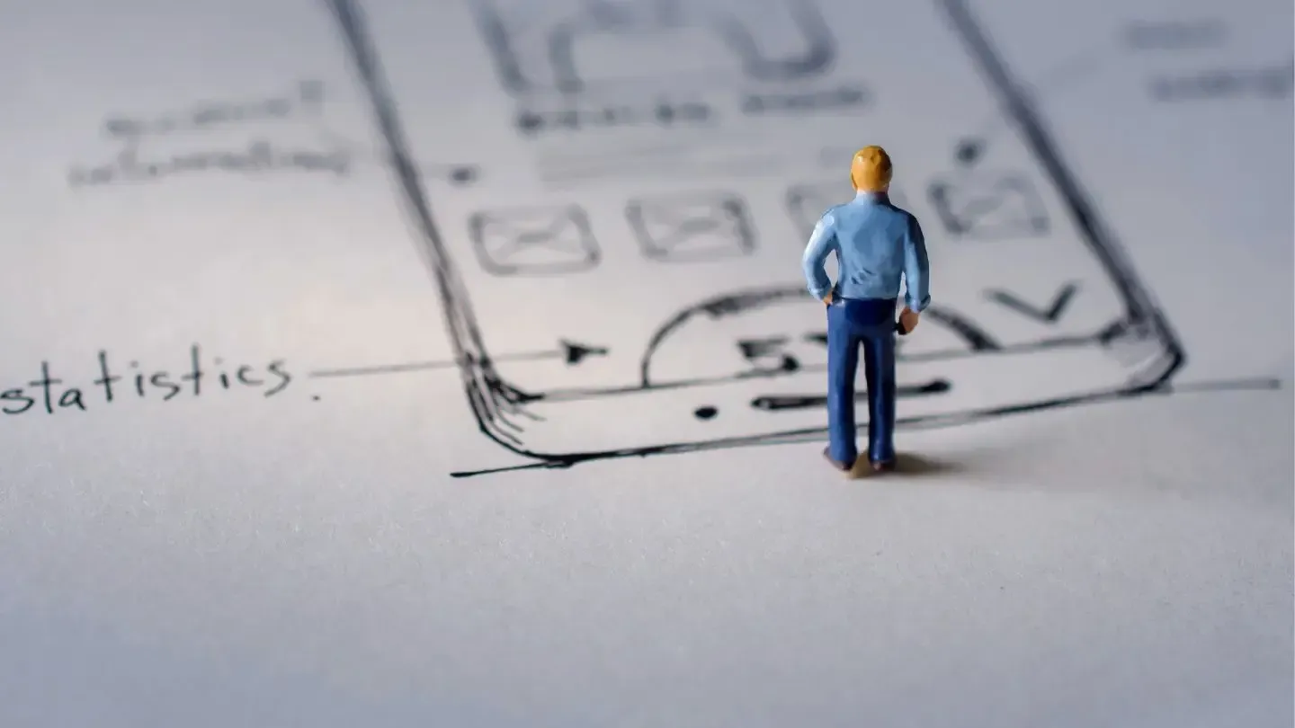 Miniature figure stands before a sketched smartphone interface, suggesting app design and development.