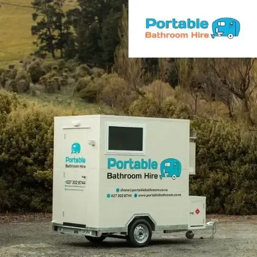 A portable bathroom hire trailer is parked in a parking lot.