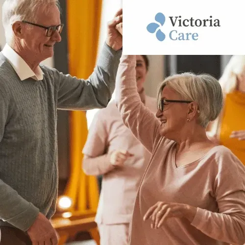 A group of people are dancing in front of a sign that says victoria care