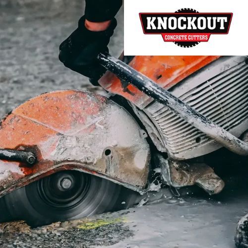 A person is using a knockout concrete cutter to cut a hole in the ground
