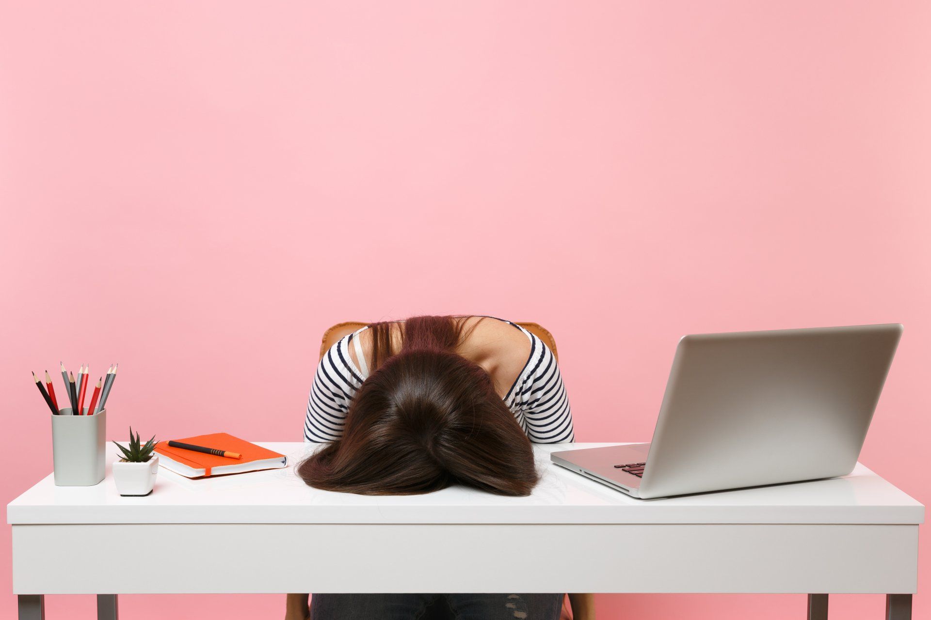 Woman with her head on the desk in frustration over under performing Google Ads campaign