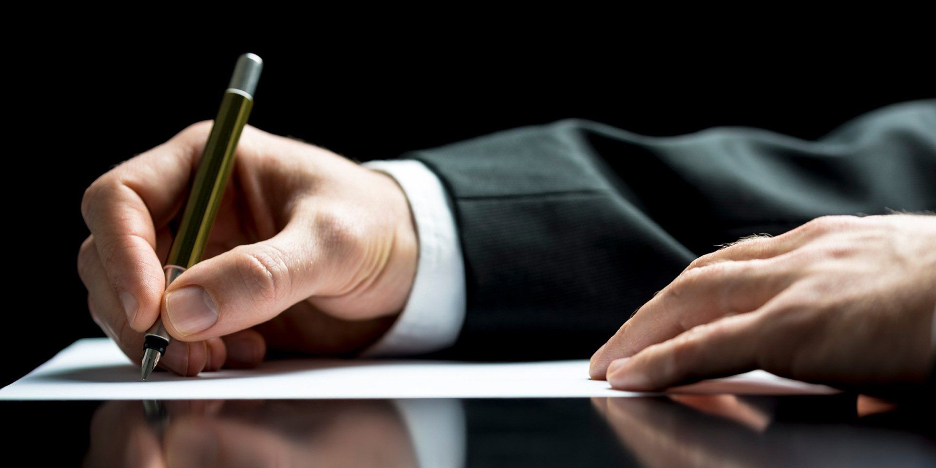 man in suit writing on a piece of paper