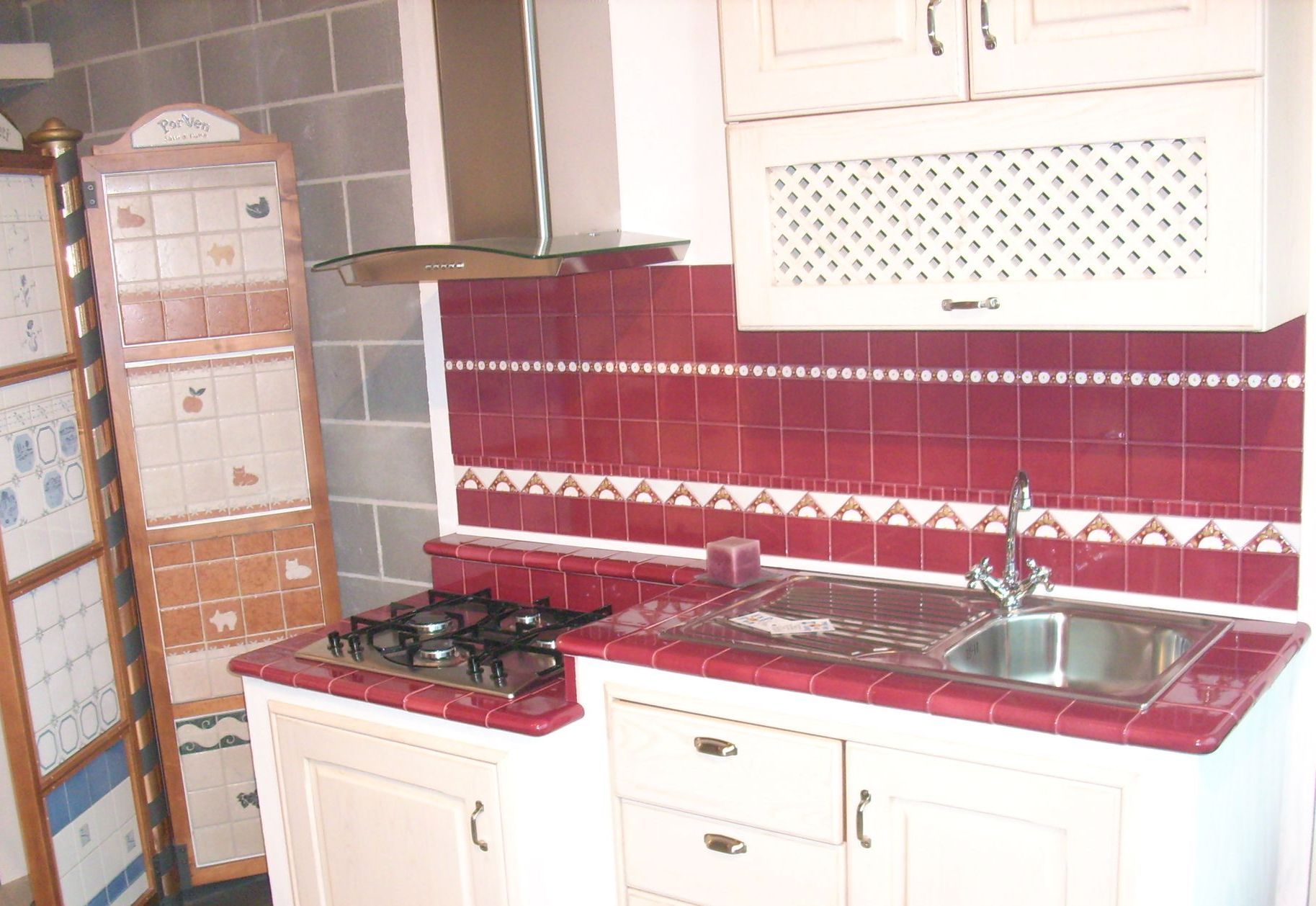 Una cucina con piastrelle rosse e mobili bianchi