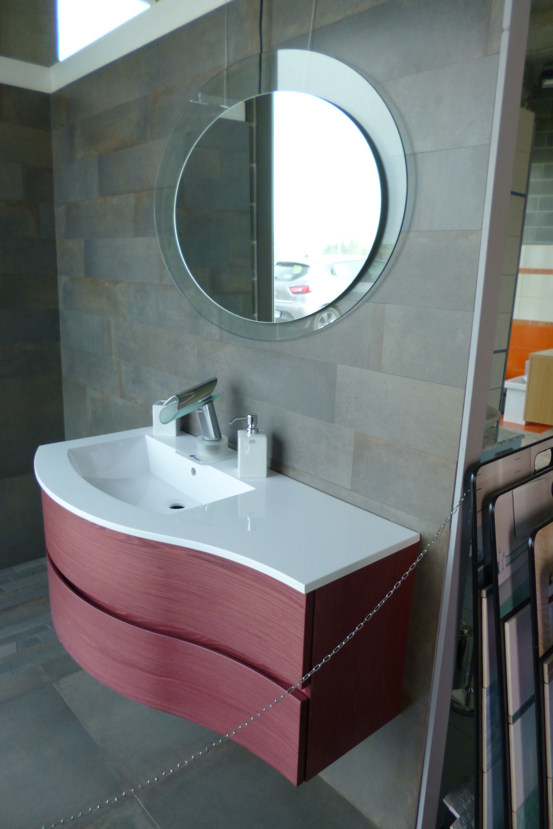 Un lavandino del bagno con uno specchio rotondo sopra