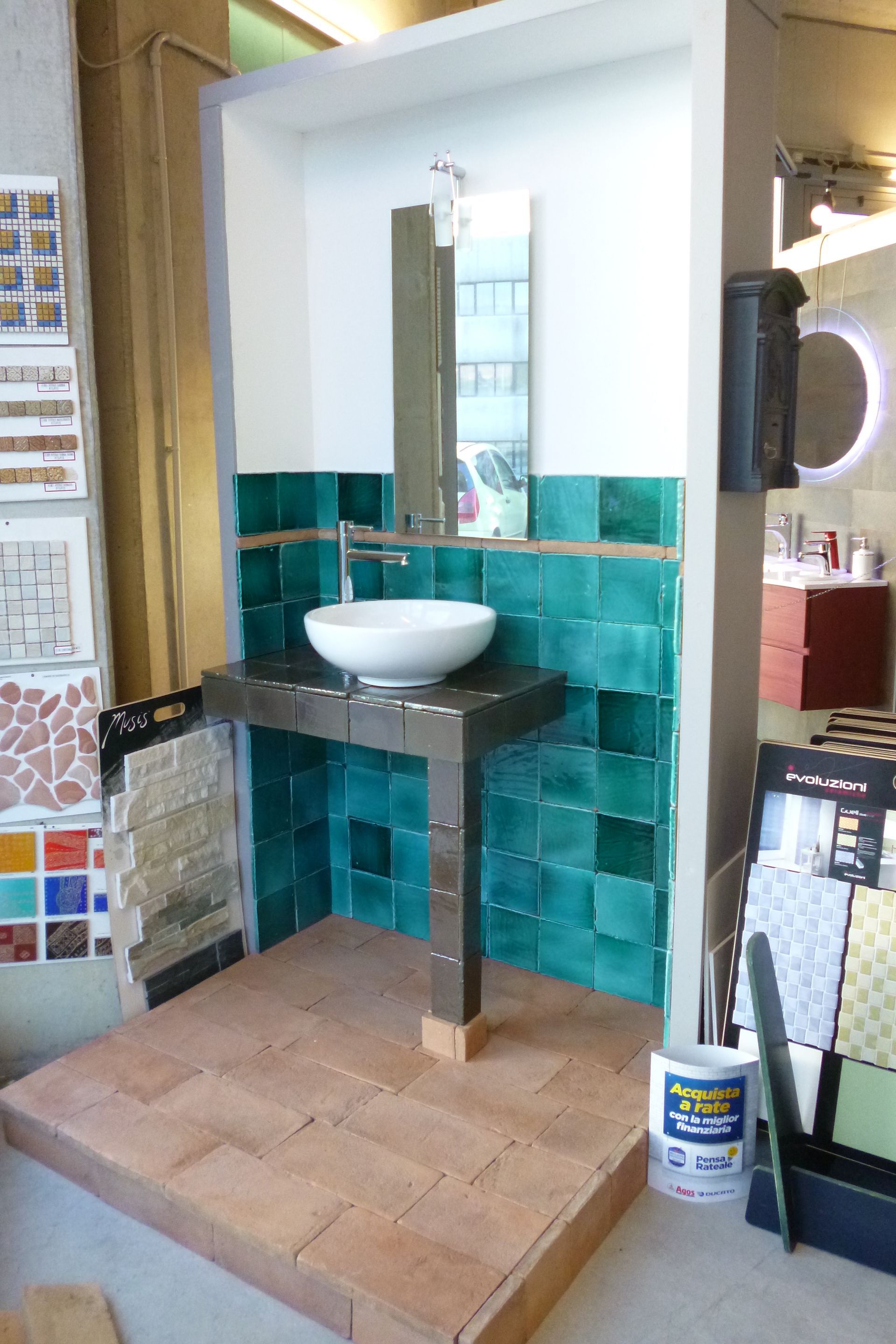 Un bagno con piastrelle verdi e un lavandino bianco