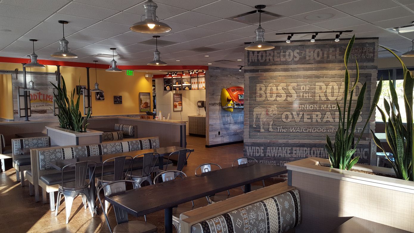 A restaurant with tables and benches and a sign on the wall.