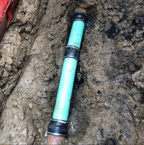 A green pipe is laying in the dirt