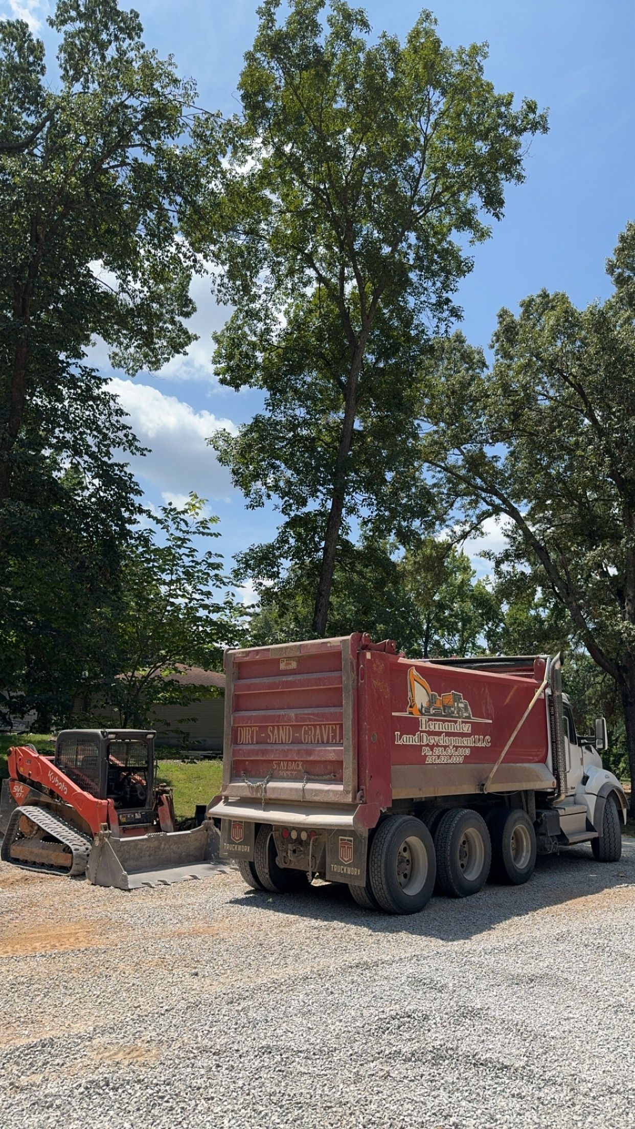 A red dump truck is parked in a gravel lot.