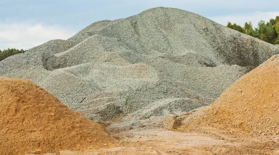 A pile of gravel and sand is sitting on top of a dirt hill.