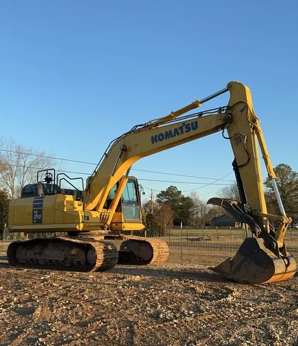 A yellow komatsu excavator is parked in a dirt field.