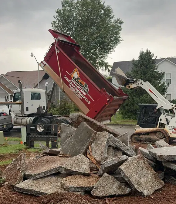 A red dumpster is being dumped into a pile of rocks