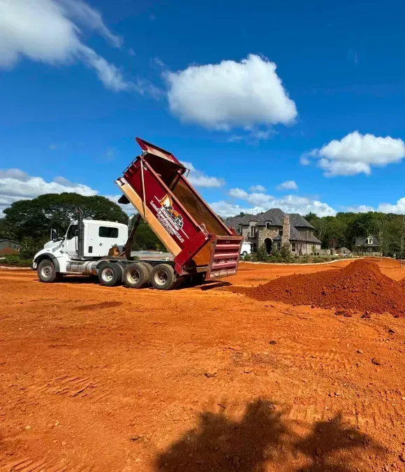 A dump truck is dumping dirt on a construction site.
