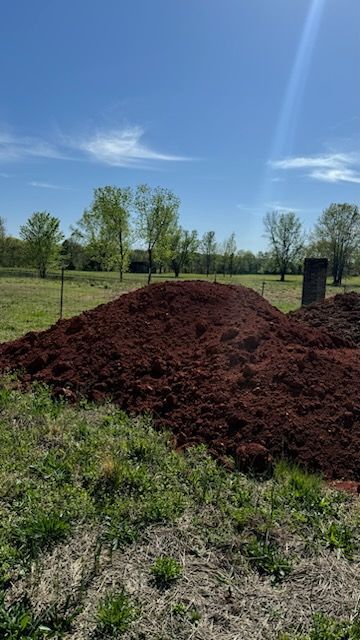 There is a large pile of dirt in the middle of a field.