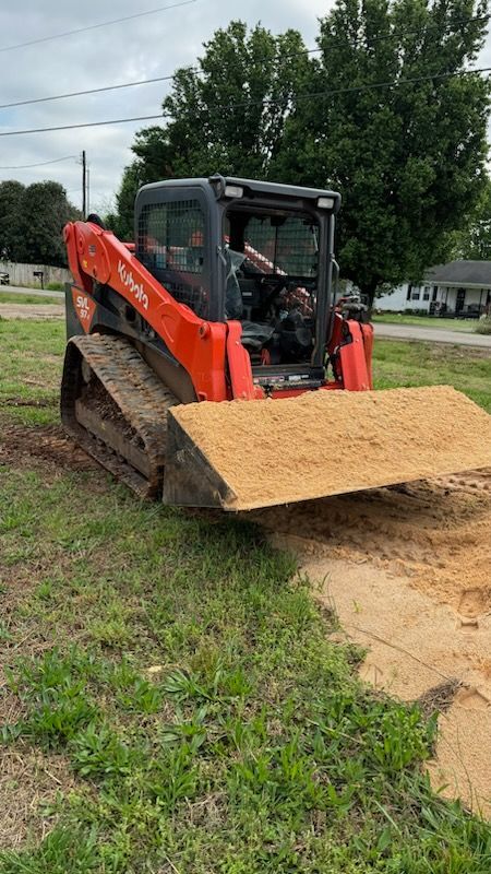 A red and black bulldozer is sitting in a grassy field.