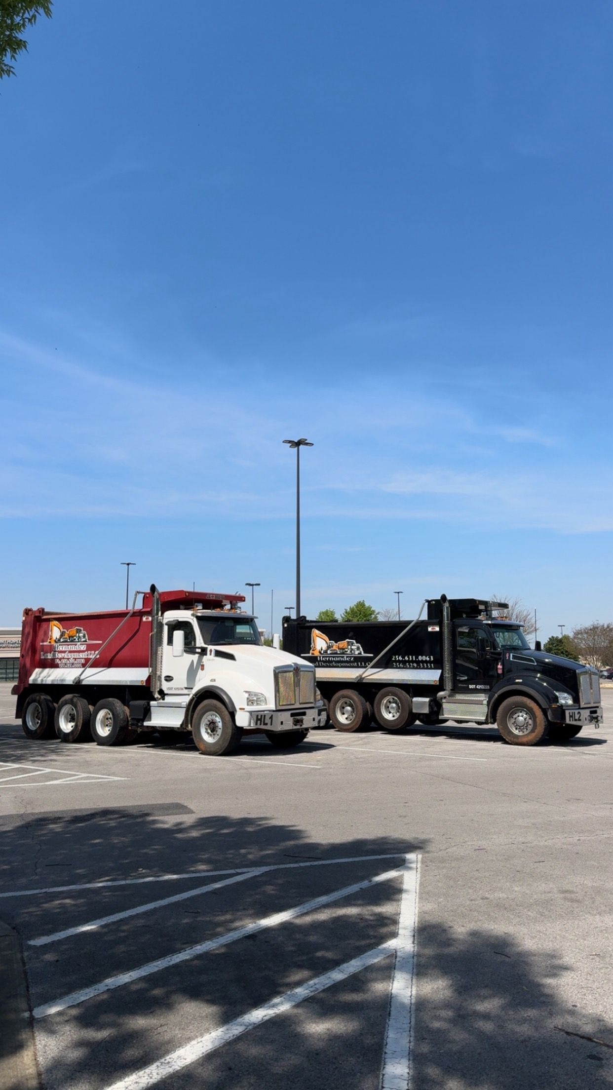 Two dump trucks are parked next to each other in a parking lot.
