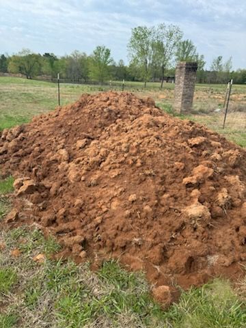 A pile of dirt is sitting in the middle of a grassy field.