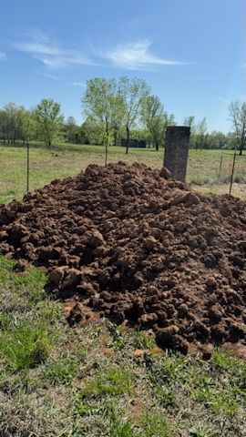 There is a large pile of dirt in the middle of a field.