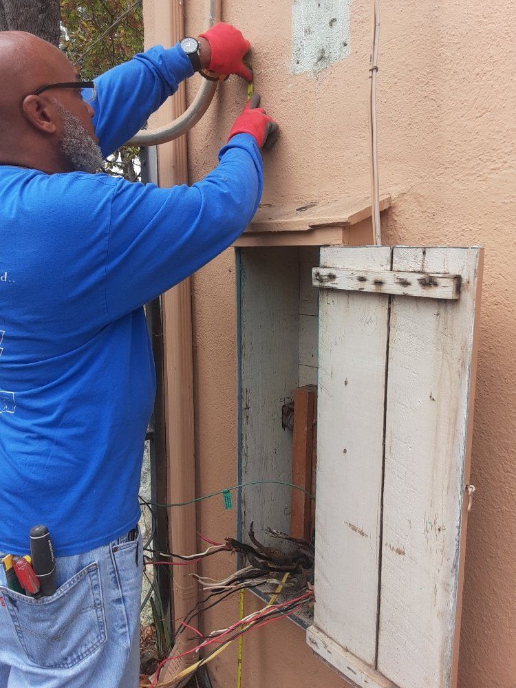 A man in a blue shirt is working on an electrical box