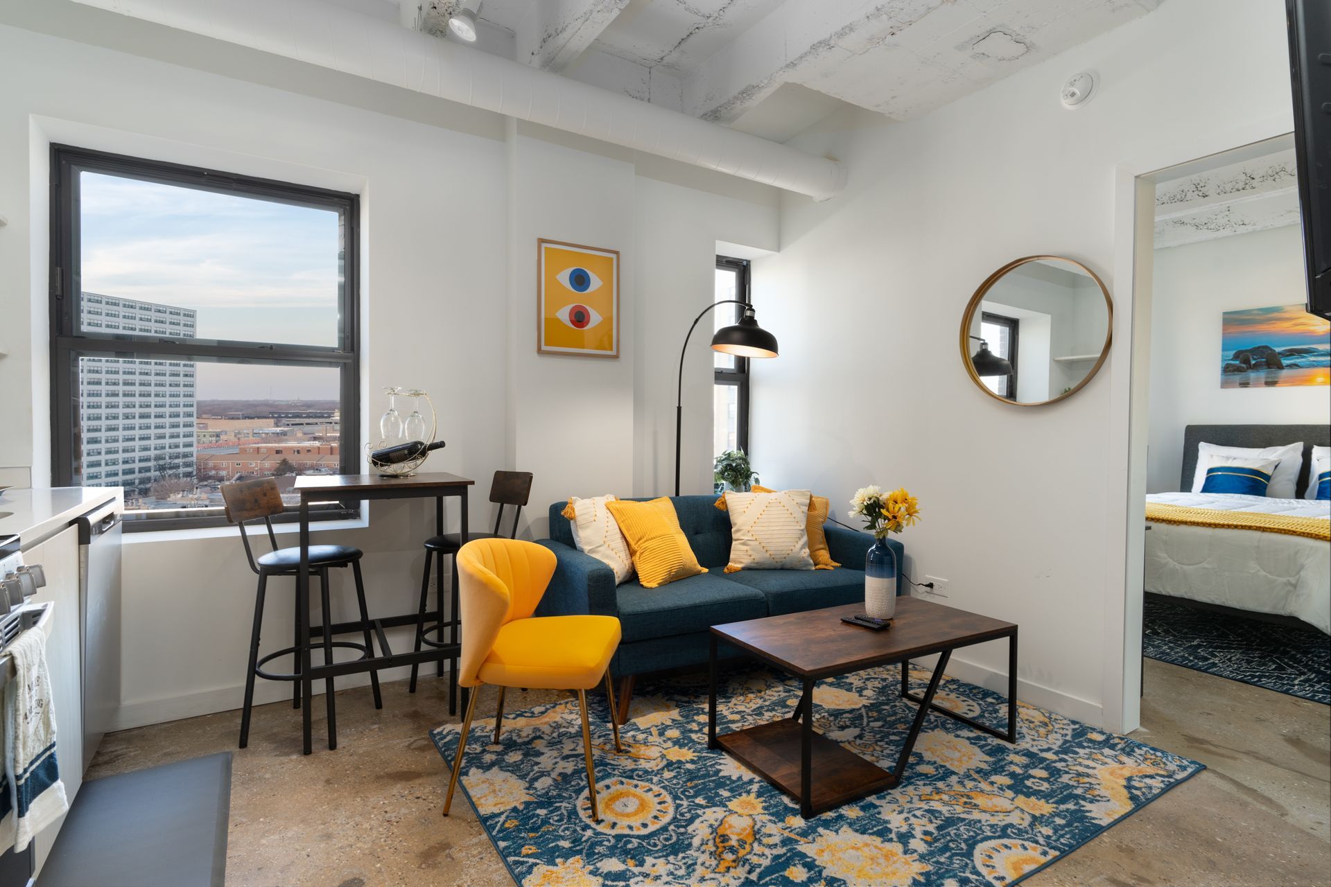 Cozy urban apartment living room with a blue sofa, yellow accents, and city views from a large window.
