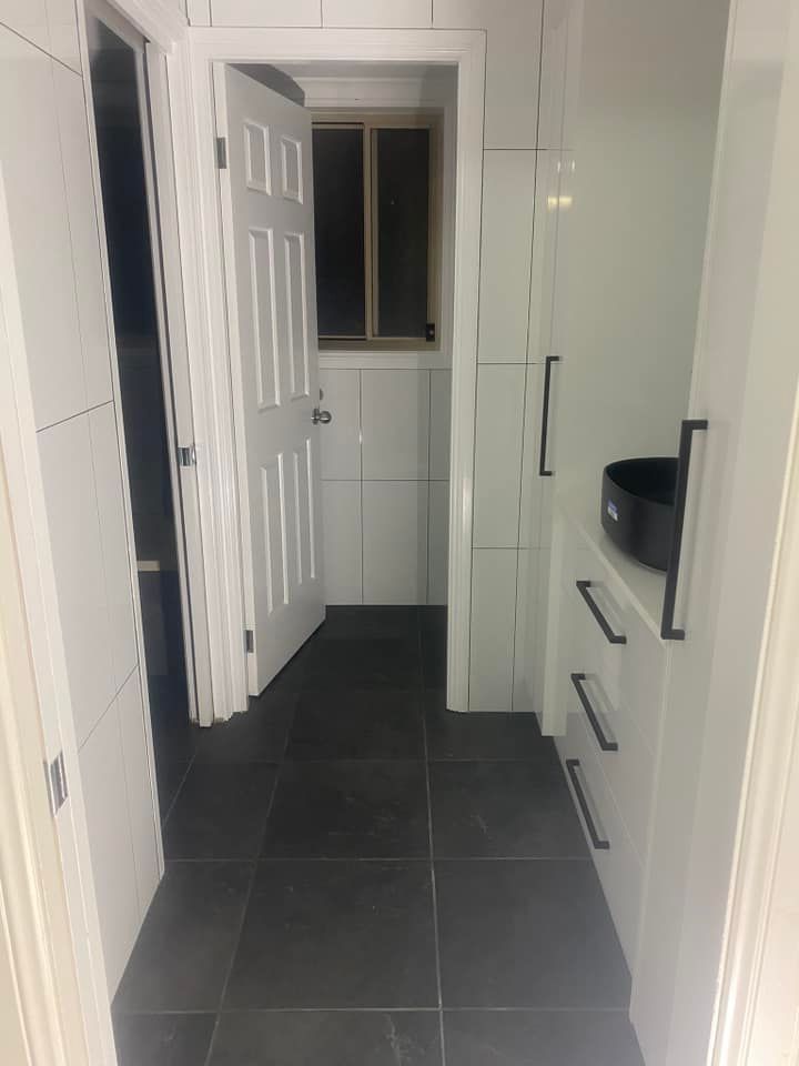 A Bathroom With Black Tile Floors and White Cabinets — 4Shaw Kitchens in Dubbo, NSW