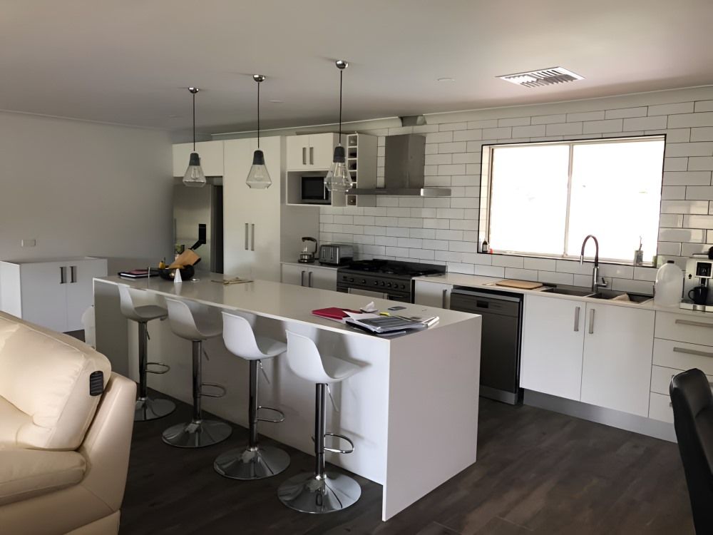 A Kitchen With White Cabinets and Stools and a Large Island — 4Shaw Kitchens in Parkes, NSW