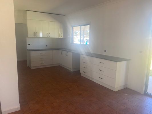 An Empty Kitchen with White Cabinets and Black Countertops — 4Shaw Kitchens in Dubbo, NSW