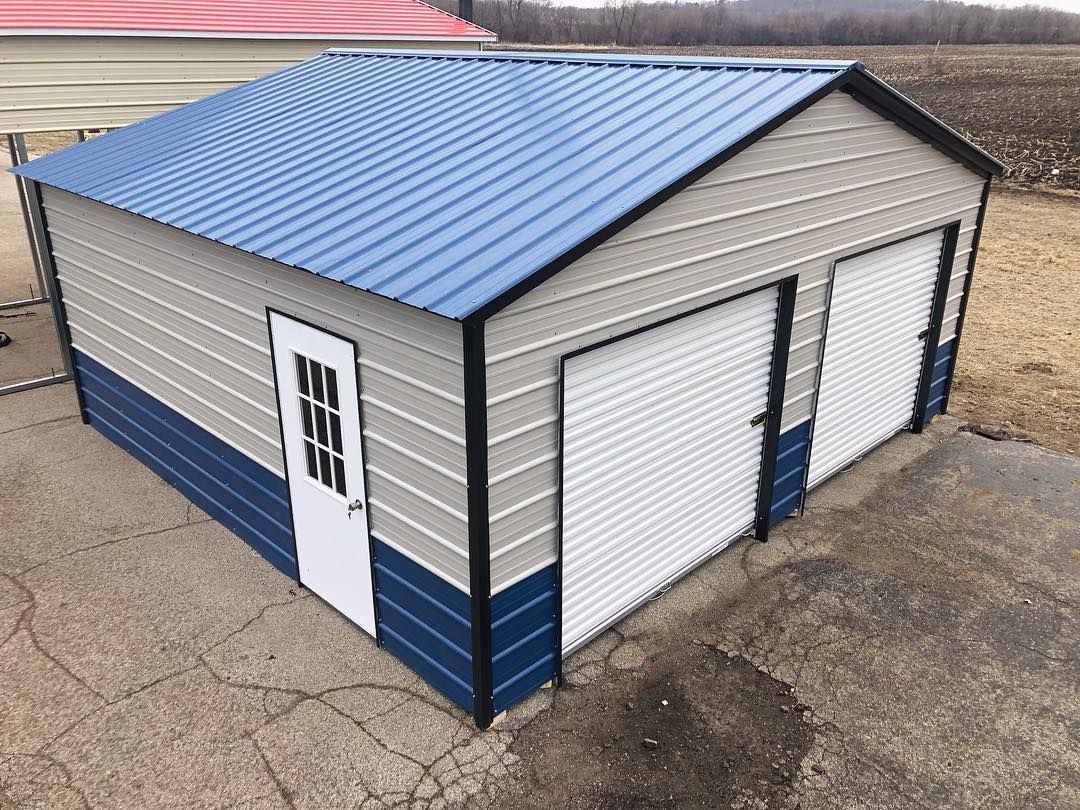 a metal garage with a blue roof and white doors .