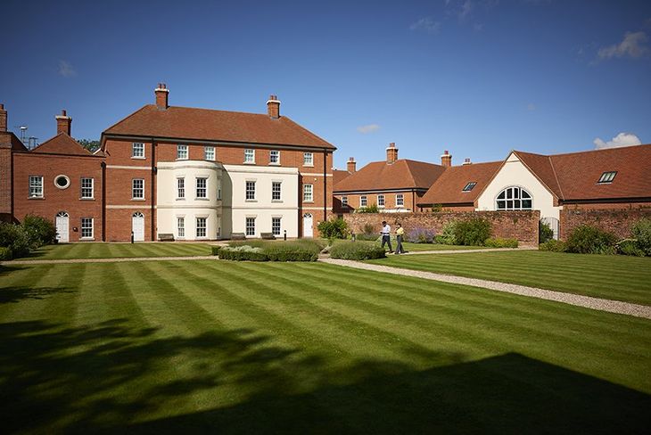 a large brick building with a lush green lawn in front of it .