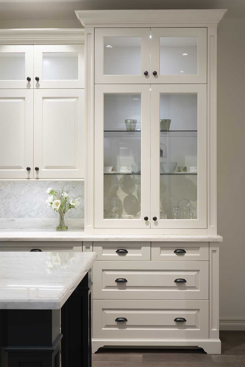 White glass fronted kitchen cabinets with drawers below