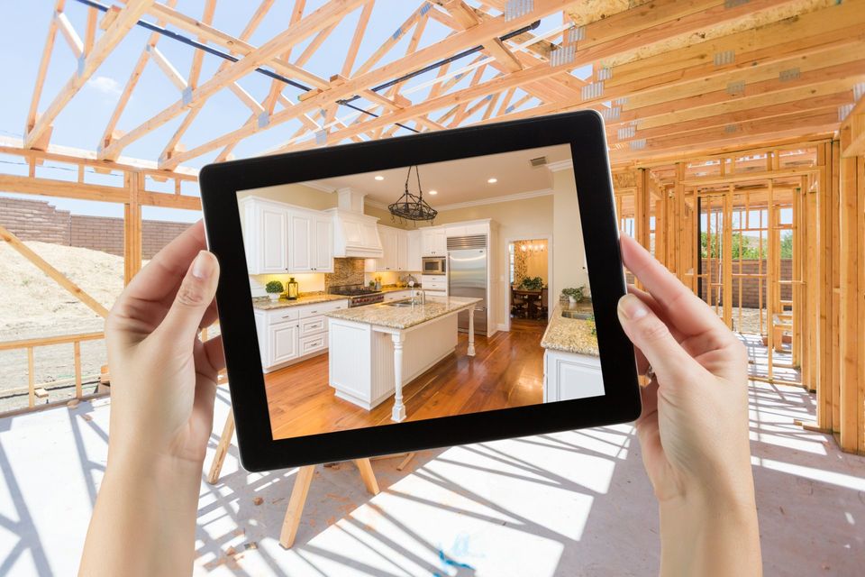 Female Hands Holding Computer Tablet with Finished Kitchen on Screen, Construction Framing Behind