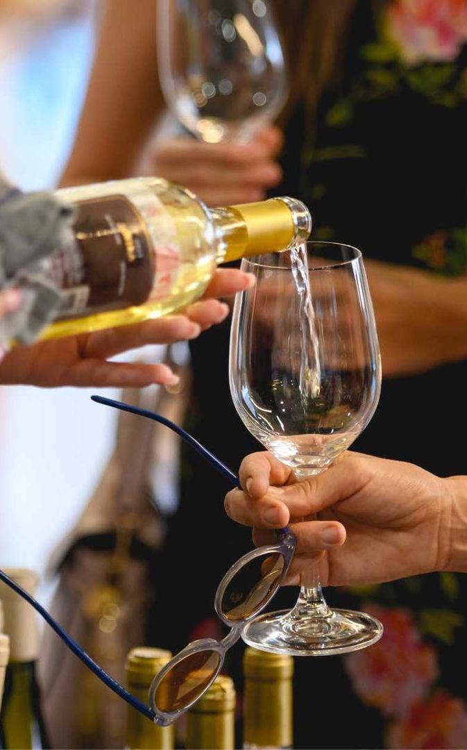 A woman is holding a bottle of wine and a glass of wine.