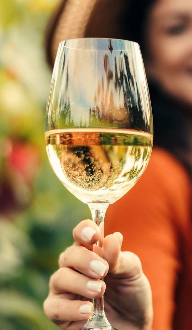 A woman is holding a bottle of wine and a glass of wine.