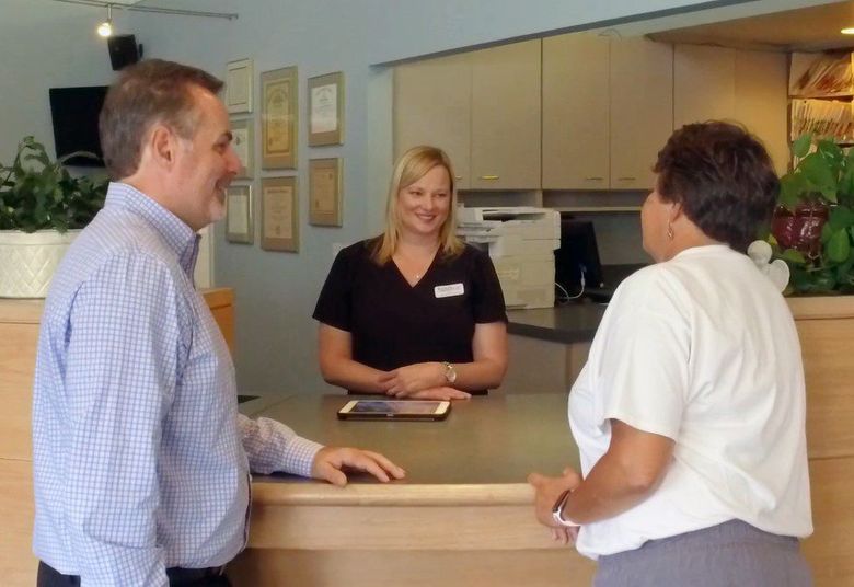 a man and woman are talking to a woman at a counter