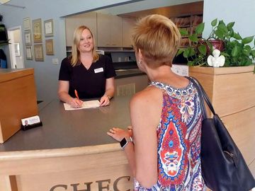 a woman is sitting at a counter talking to another woman