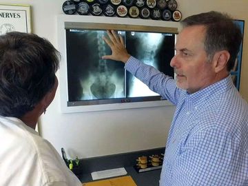 a man is pointing at an x-ray of a person 's back