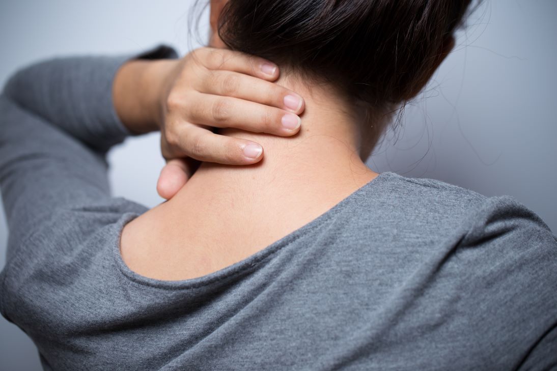 a woman is holding her neck in pain because of a headache .