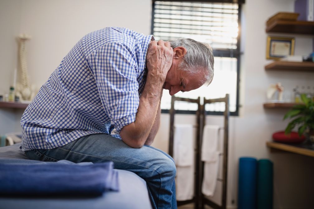 an older man is sitting on a table with his head down .