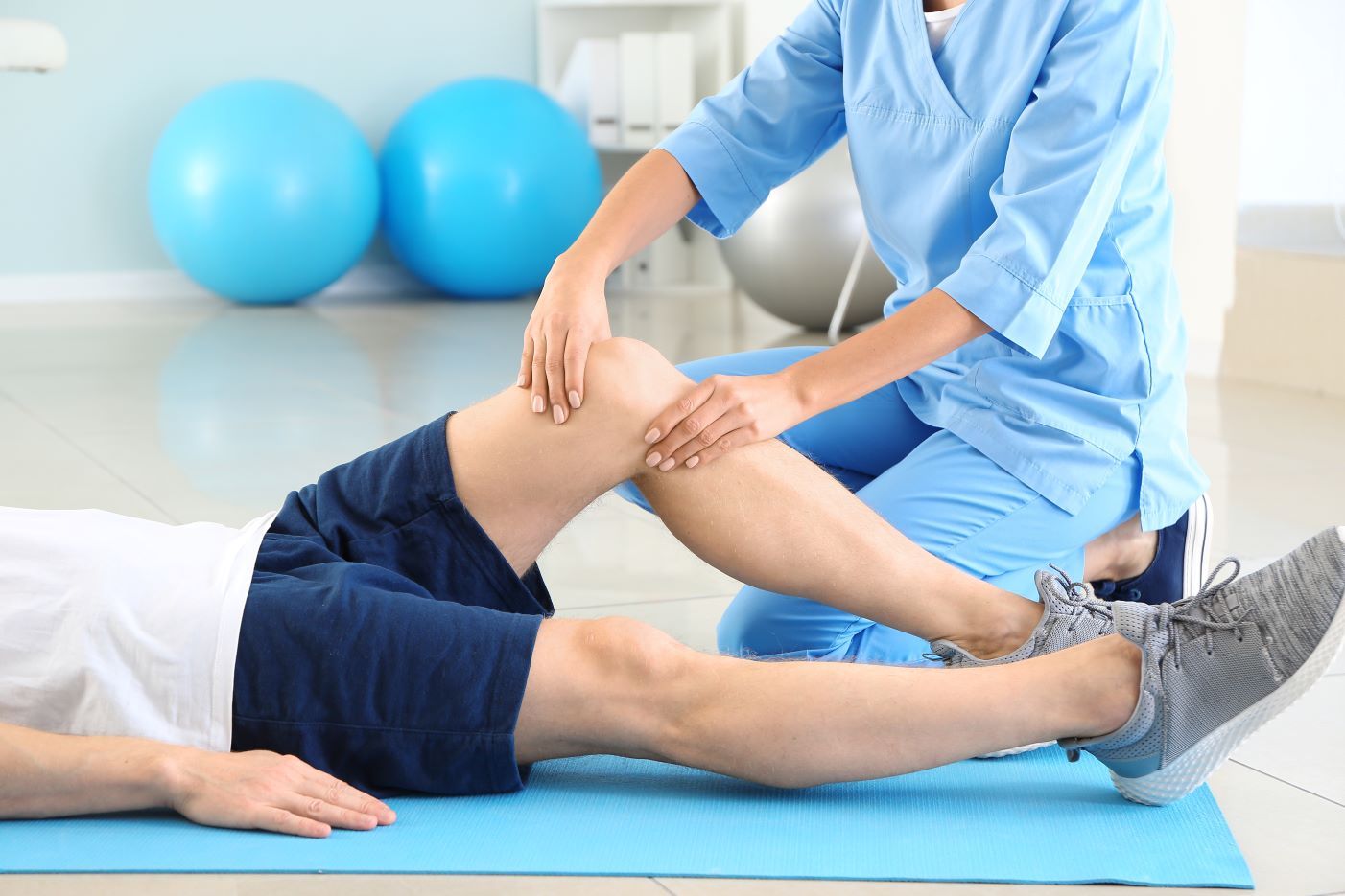 a nurse is examining a patient 's knee in a gym .