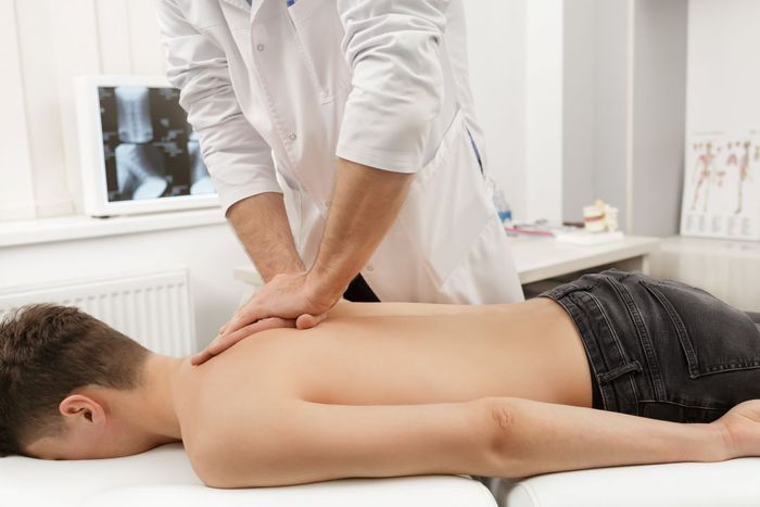 a young boy is getting a massage from a doctor .