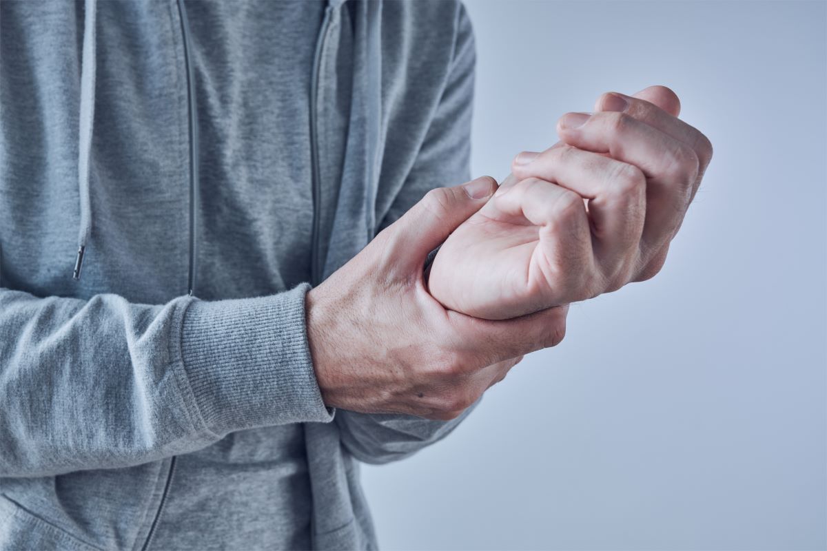 a man is holding his wrist in pain .