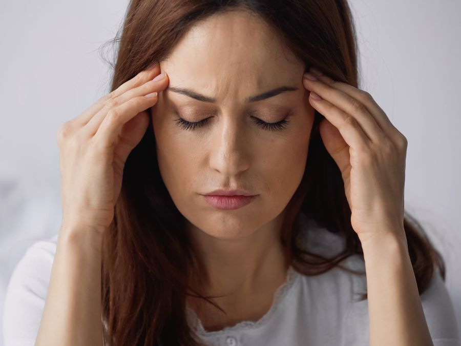 a woman is holding her head because she has a headache .