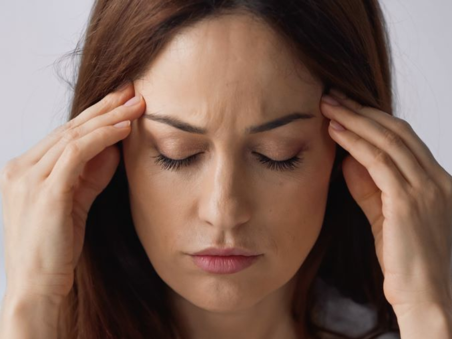 Woman with closed eyes, holding temples, appears to be in pain or experiencing headache in Hope Mills, NC.