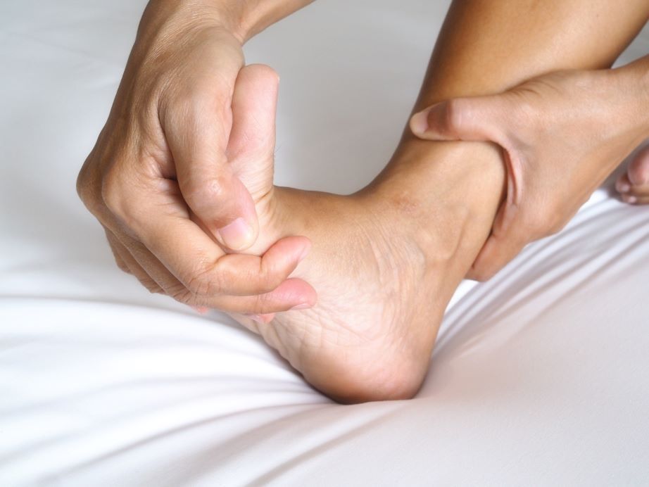 a person is holding their foot in pain on a bed