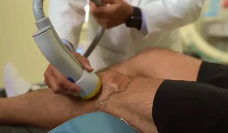 A doctor is examining a patient 's knee with a machine.
