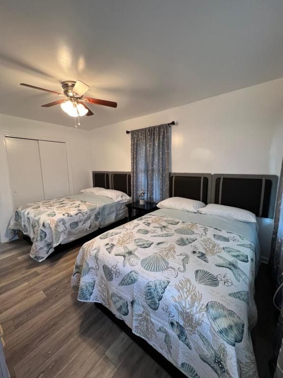 A bedroom with two beds and a ceiling fan.