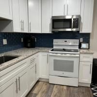 A kitchen with white cabinets , a stove , microwave and sink.