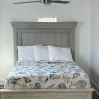 A bed with a gray headboard and a ceiling fan in a bedroom.